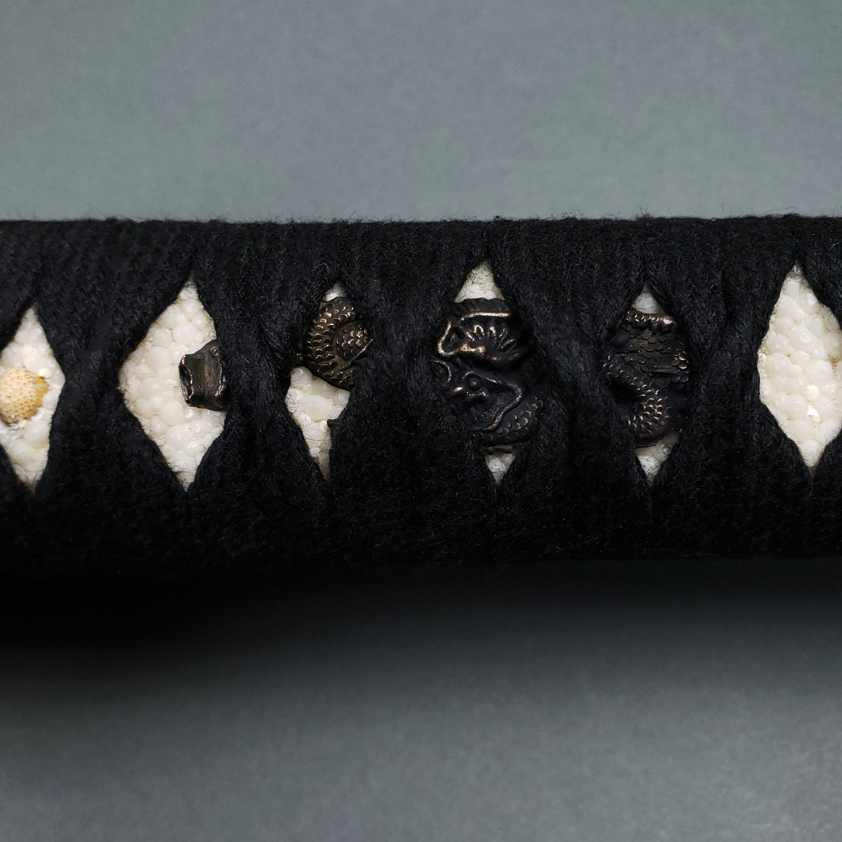 Close-up of Musashi Tsuru Katana handle with black tsuka-ito and ray skin grip showcasing detailed menuki