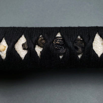 Close-up of Musashi Tsuru Katana handle with black tsuka-ito and ray skin grip showcasing detailed menuki